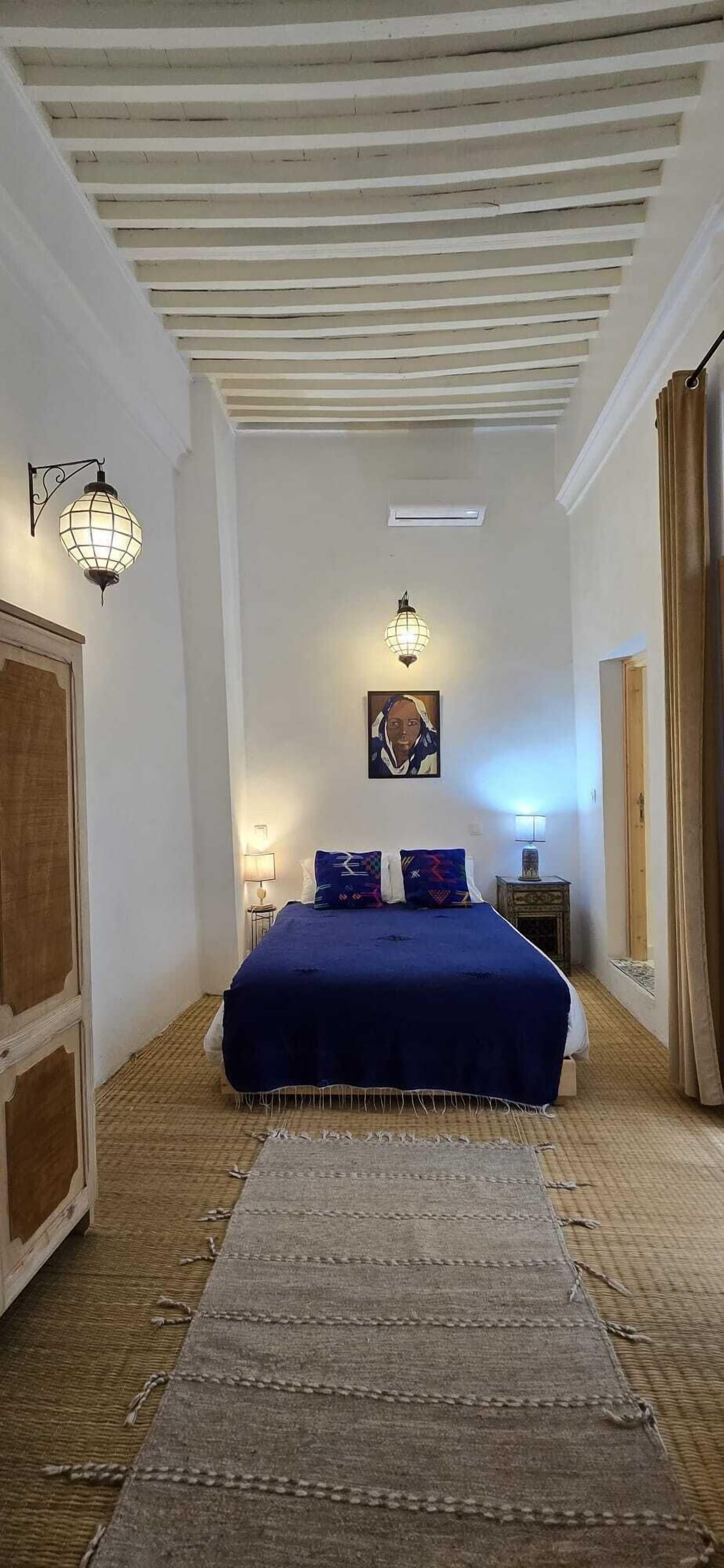 Chambre bleue avec charpente en bois apparente et literie soignée — La Maison des Amis
